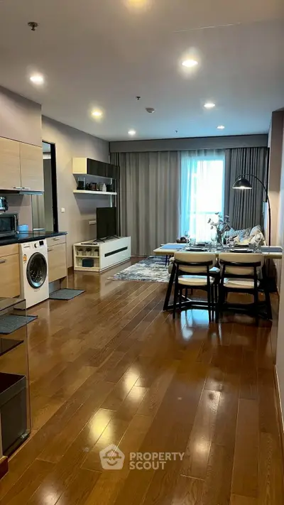 Modern open-plan living room with kitchen, featuring hardwood floors and stylish furniture.