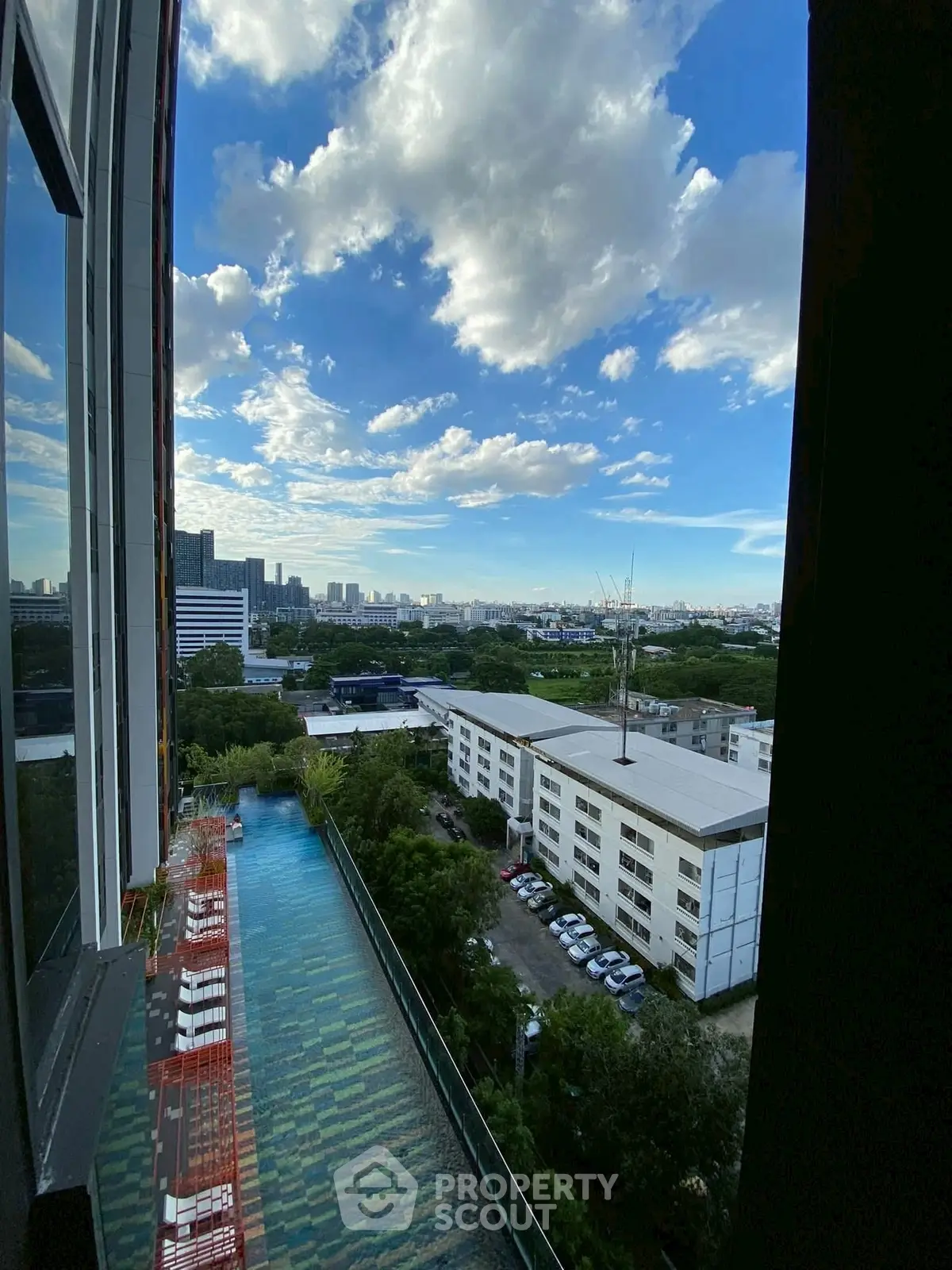 Stunning cityscape view from high-rise building with infinity pool and lush greenery.