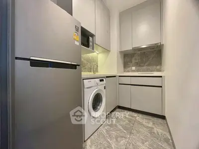 Modern kitchen with sleek appliances and washing machine in compact layout
