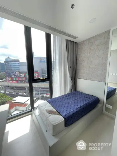 Modern bedroom with large windows offering a dynamic city view, sleek design, and ample natural light, perfect for urban living.