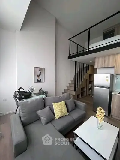 Modern loft apartment with stylish living area and mezzanine, featuring sleek furniture and contemporary design.