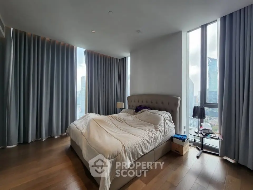 Luxurious bedroom with floor-to-ceiling windows and city view, featuring elegant curtains and modern decor.
