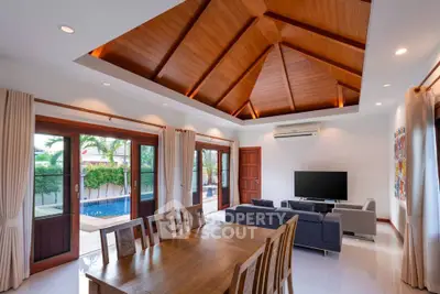Spacious living room with wooden ceiling and pool view, perfect for modern living.