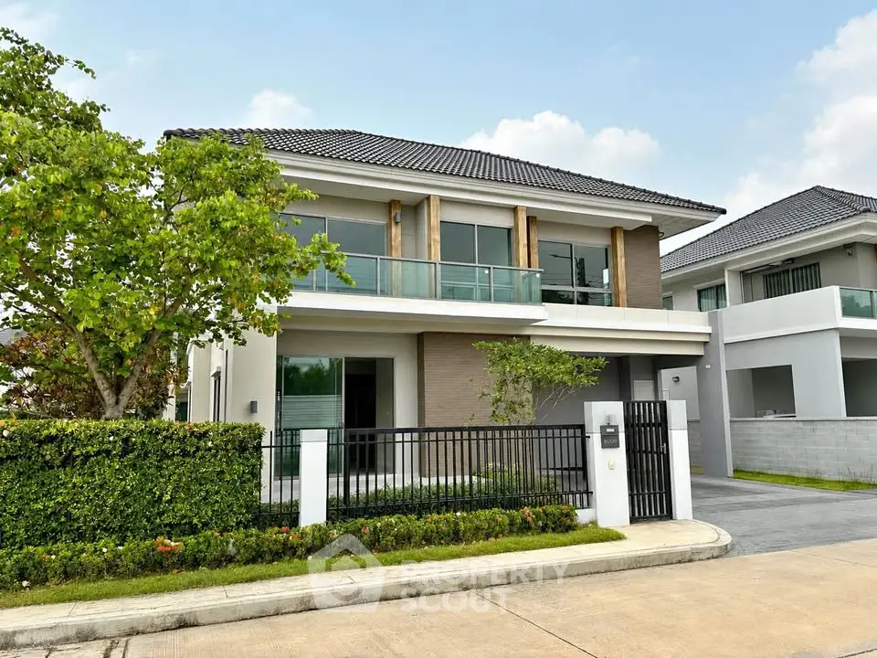 Modern two-story house with large windows and landscaped front yard in a serene neighborhood.