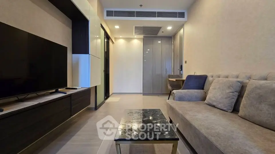 Modern living room with sleek furniture and large TV in a stylish apartment.