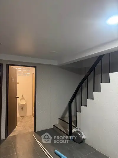 Modern interior with staircase and bathroom entrance, featuring sleek design and neutral tones.
