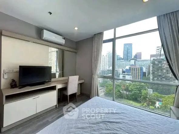 Modern bedroom with large window offering stunning city view in high-rise apartment.