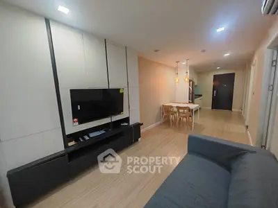 Modern living room with sleek furniture and open layout leading to dining area.