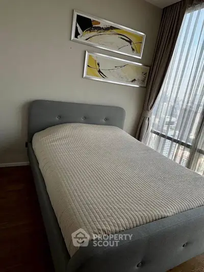 Cozy bedroom with modern decor and large window offering city views.