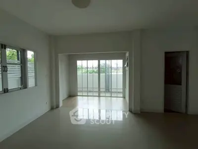 Spacious empty room with large windows and sliding glass doors leading to a small balcony.