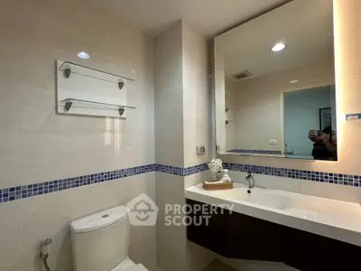 Modern bathroom with sleek fixtures and large mirror, featuring elegant tile design and ample lighting.