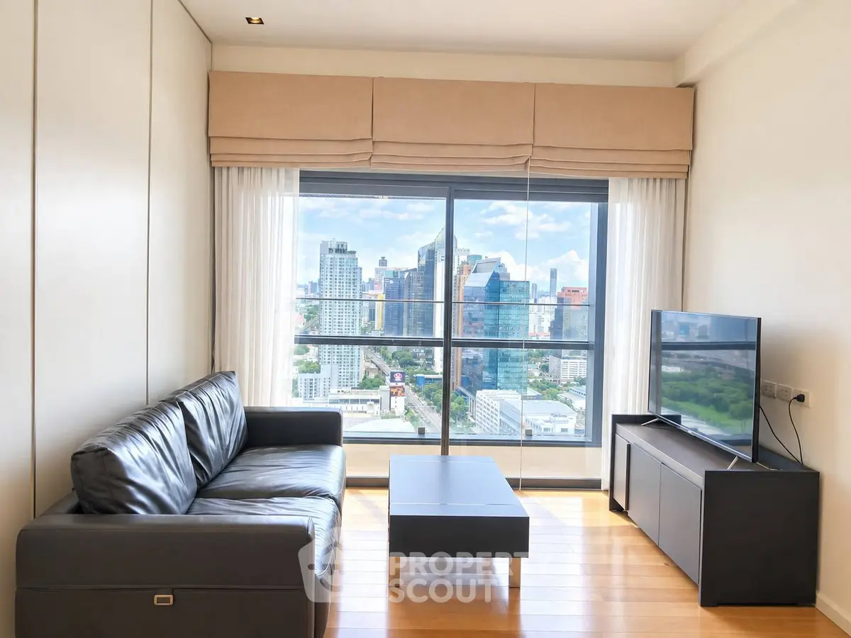 Modern living room with city view, featuring sleek black leather sofa and flat-screen TV.