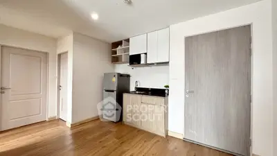 Modern compact kitchen with sleek cabinetry and stainless steel fridge in cozy apartment.