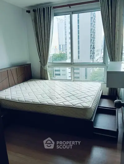 Modern bedroom with large window and city view, featuring a comfortable bed and stylish decor.