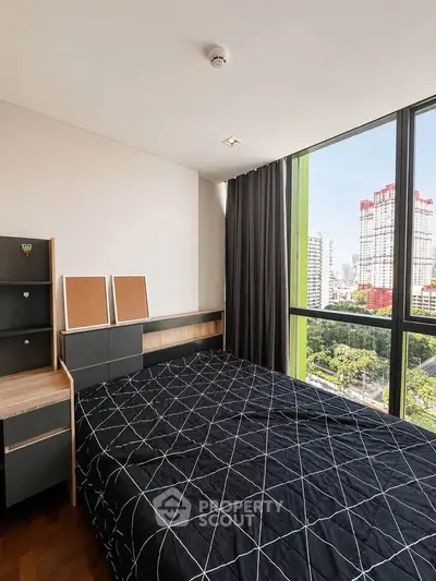 Modern bedroom with large window offering stunning city view, featuring stylish furniture and elegant decor.
