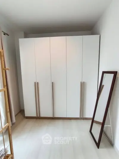 Spacious bedroom with modern wardrobe and full-length mirror, perfect for stylish living.