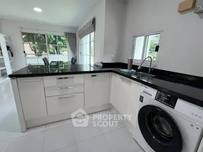 Modern kitchen with sleek countertops and built-in washing machine, offering a bright and functional space.