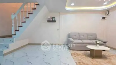 Spacious living room with modern staircase and cozy sofa in elegant home interior.