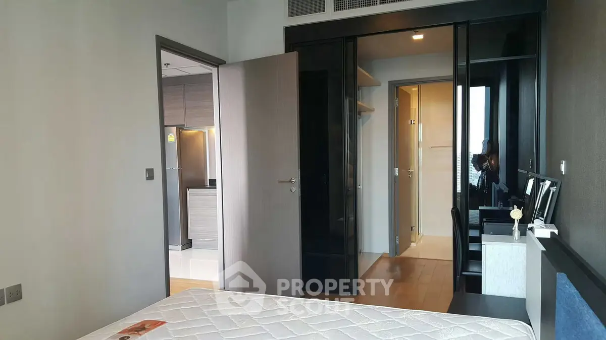 Modern bedroom with sleek design and adjacent kitchen view