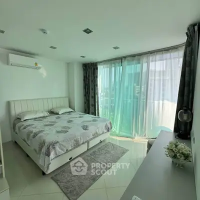 Spacious bedroom with large windows and modern decor in a high-rise apartment.