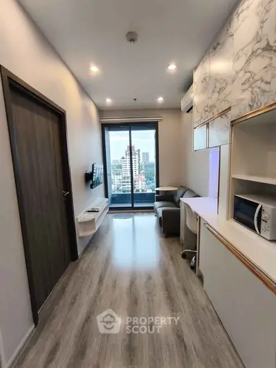 Modern living room with city view, sleek flooring, and compact furniture in a high-rise apartment.