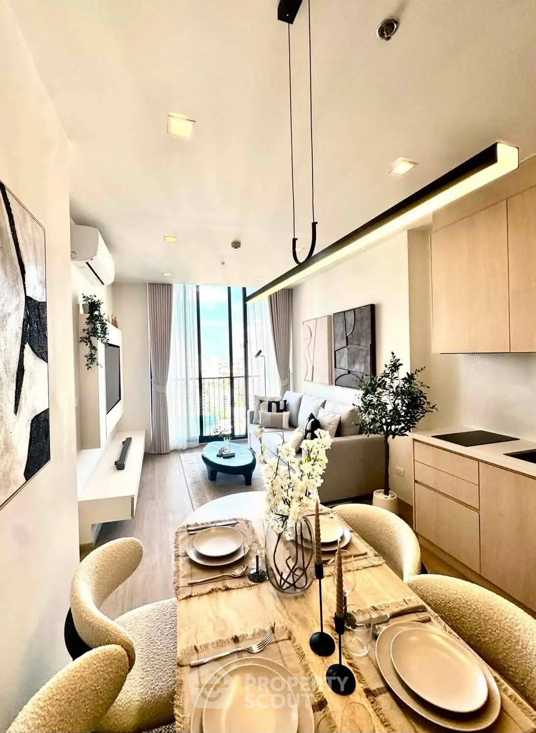 Modern open-plan living room with dining area, stylish decor, and large windows offering natural light.