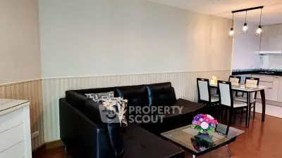 Modern living room with black leather sofa and dining area in open layout apartment.
