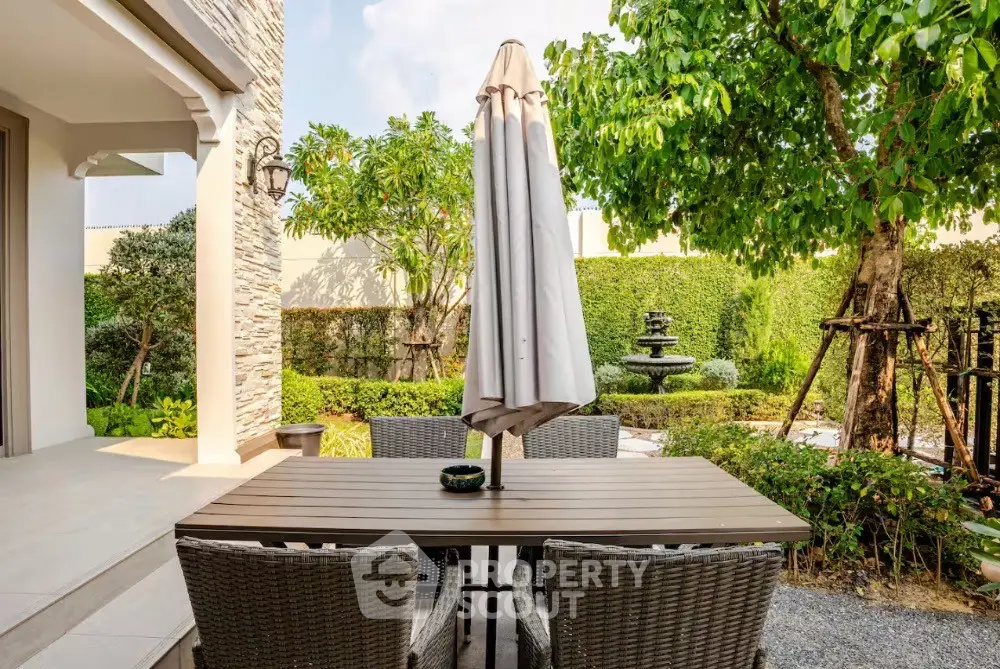 Charming outdoor patio with elegant dining set and lush garden view, perfect for relaxation and entertaining.