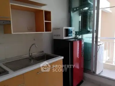 Modern kitchen with sleek red fridge and microwave, featuring open shelving and a balcony view.