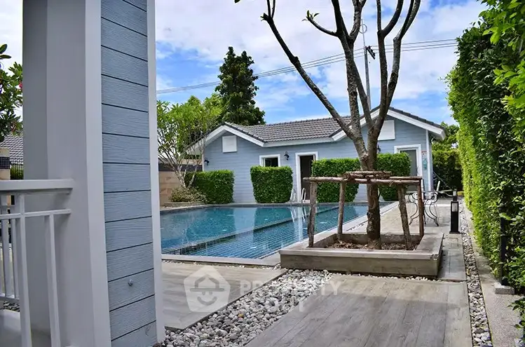 Charming blue house with a serene pool and lush greenery, perfect for relaxation and outdoor enjoyment.