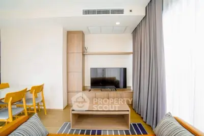 Modern living room with stylish furniture and natural light, featuring a cozy seating area and a sleek TV setup.