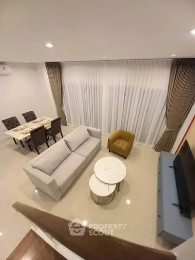 Modern living room with elegant furniture and dining area, featuring a cozy ambiance and stylish decor.