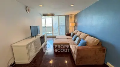 Cozy living room with modern sofa and TV, leading to a balcony with natural light.