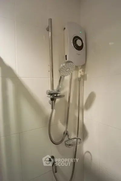 Modern bathroom with sleek electric shower unit and adjustable shower head, featuring clean white tiles for a minimalist aesthetic.
