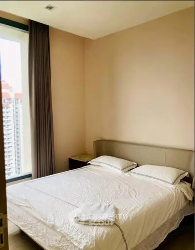 Cozy bedroom with large window and modern decor in high-rise apartment.