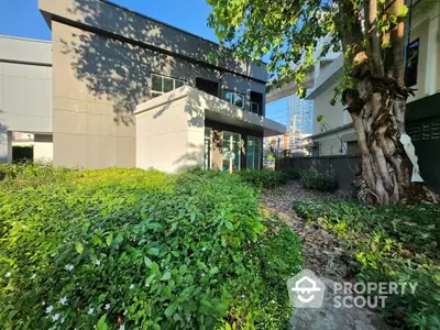 Lush green garden space in front of a modern residential building, offering a tranquil outdoor area for relaxation and community activities.