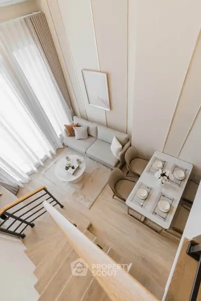 Elegant modern living room with dining area and staircase, featuring neutral tones and natural light.