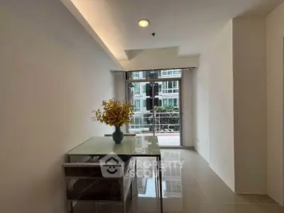 Modern apartment interior with glass table and balcony view, featuring sleek design and natural light.