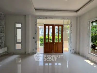 Spacious living room with elegant wooden doors and large windows offering garden views.