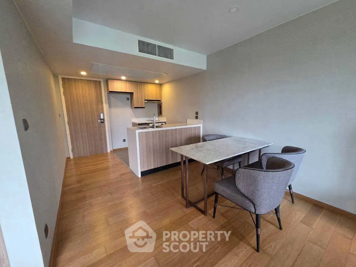Modern open-layout kitchen and dining area with wooden flooring and stylish furniture.