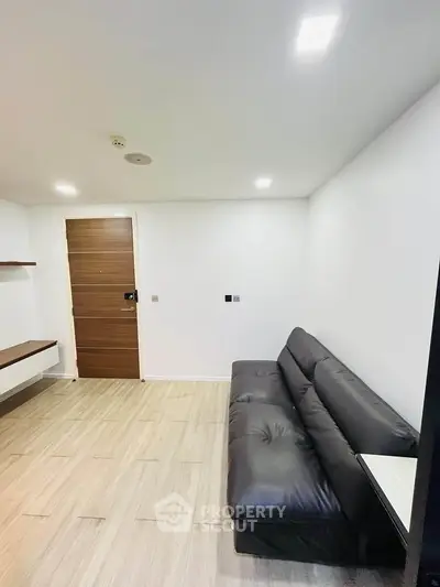 Modern living room with sleek black sofa and wooden flooring, perfect for urban living.