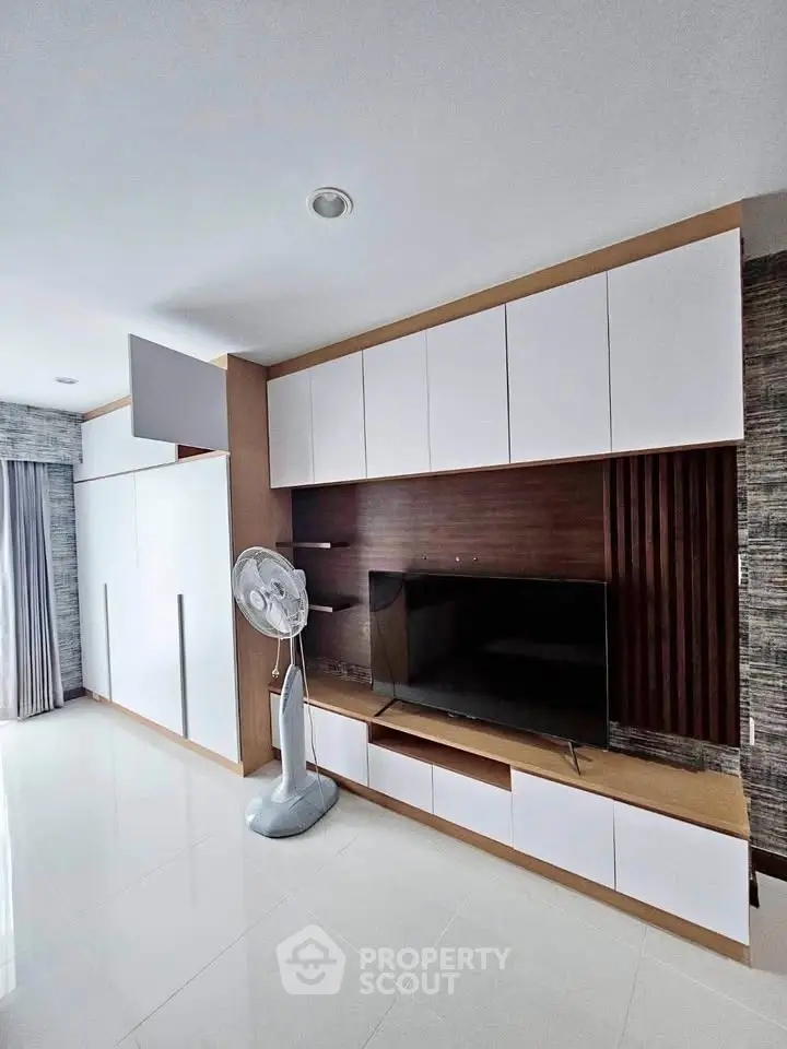 Modern living room with sleek white cabinetry and flat-screen TV