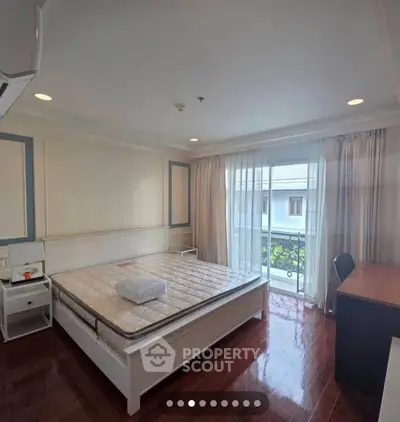 Spacious bedroom with balcony access and elegant wooden flooring.