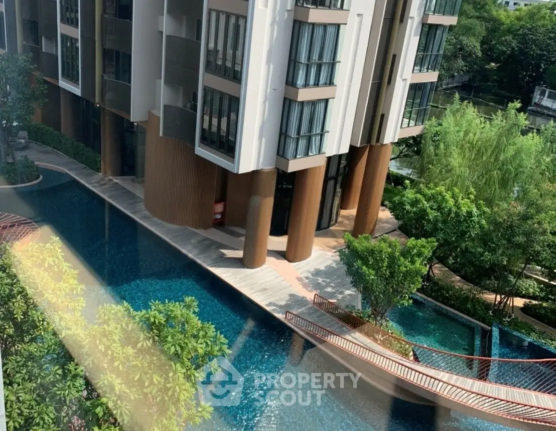 Luxurious residential building with stunning pool and lush greenery, offering a serene urban oasis.