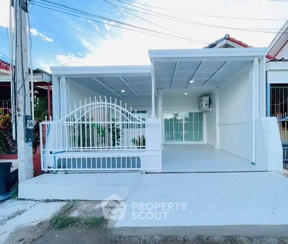 Modern white exterior of a single-story home with gated entrance and carport.