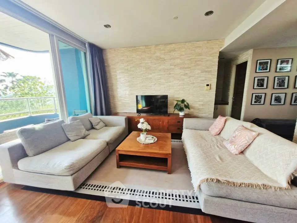 Spacious living room with modern decor and large windows offering natural light and a view.