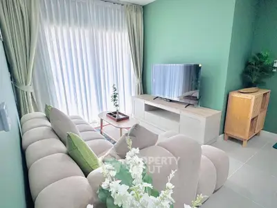 Modern living room with plush sofa, TV, and green accent wall
