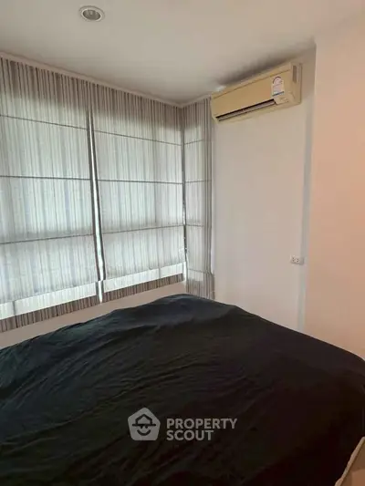 Cozy bedroom with air conditioning and natural light through sheer curtains.