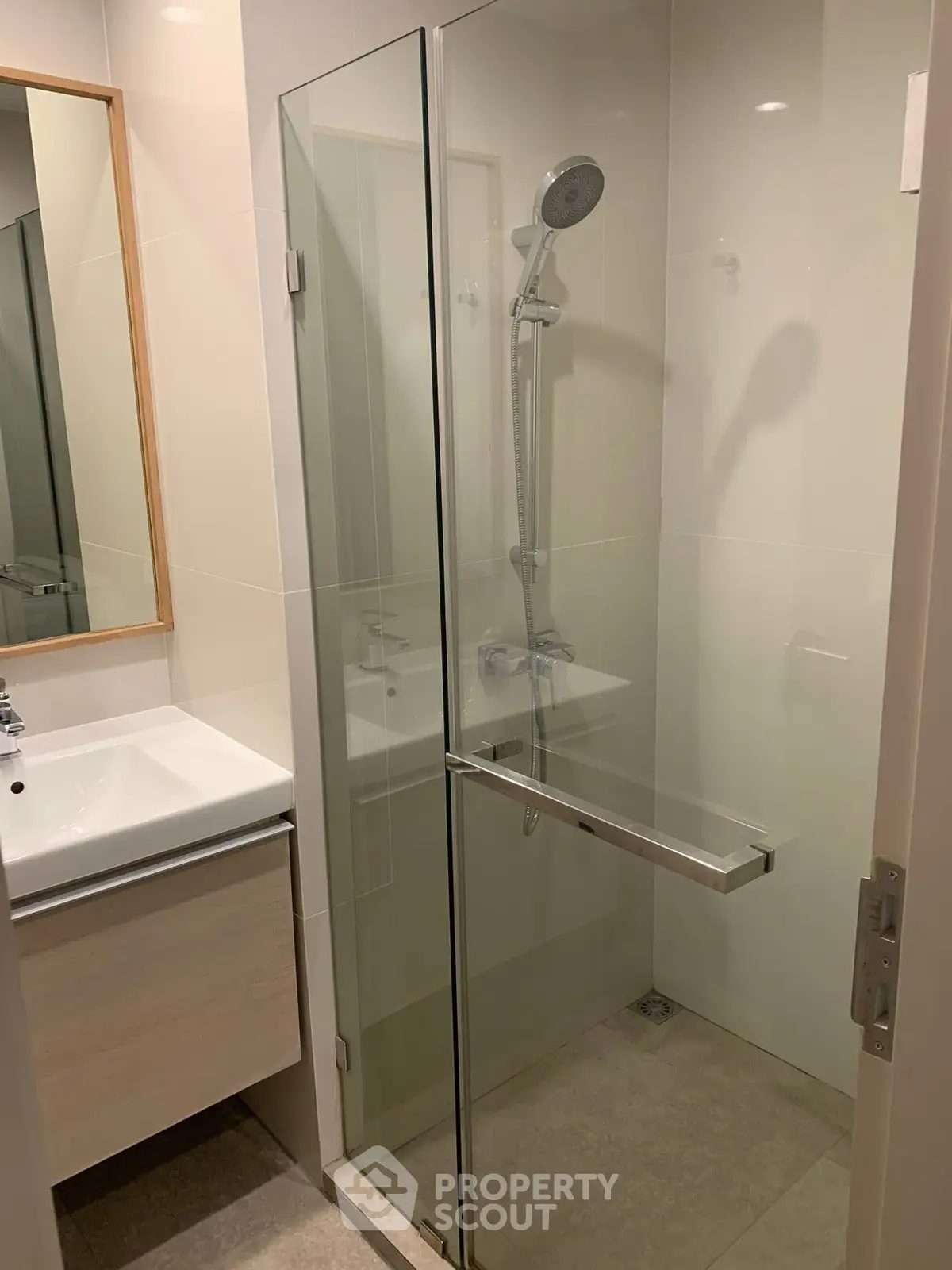 Modern bathroom with glass shower enclosure and sleek vanity in a contemporary apartment.