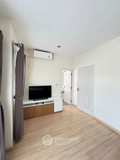 Modern living room with wooden flooring and mounted TV, minimalistic design.